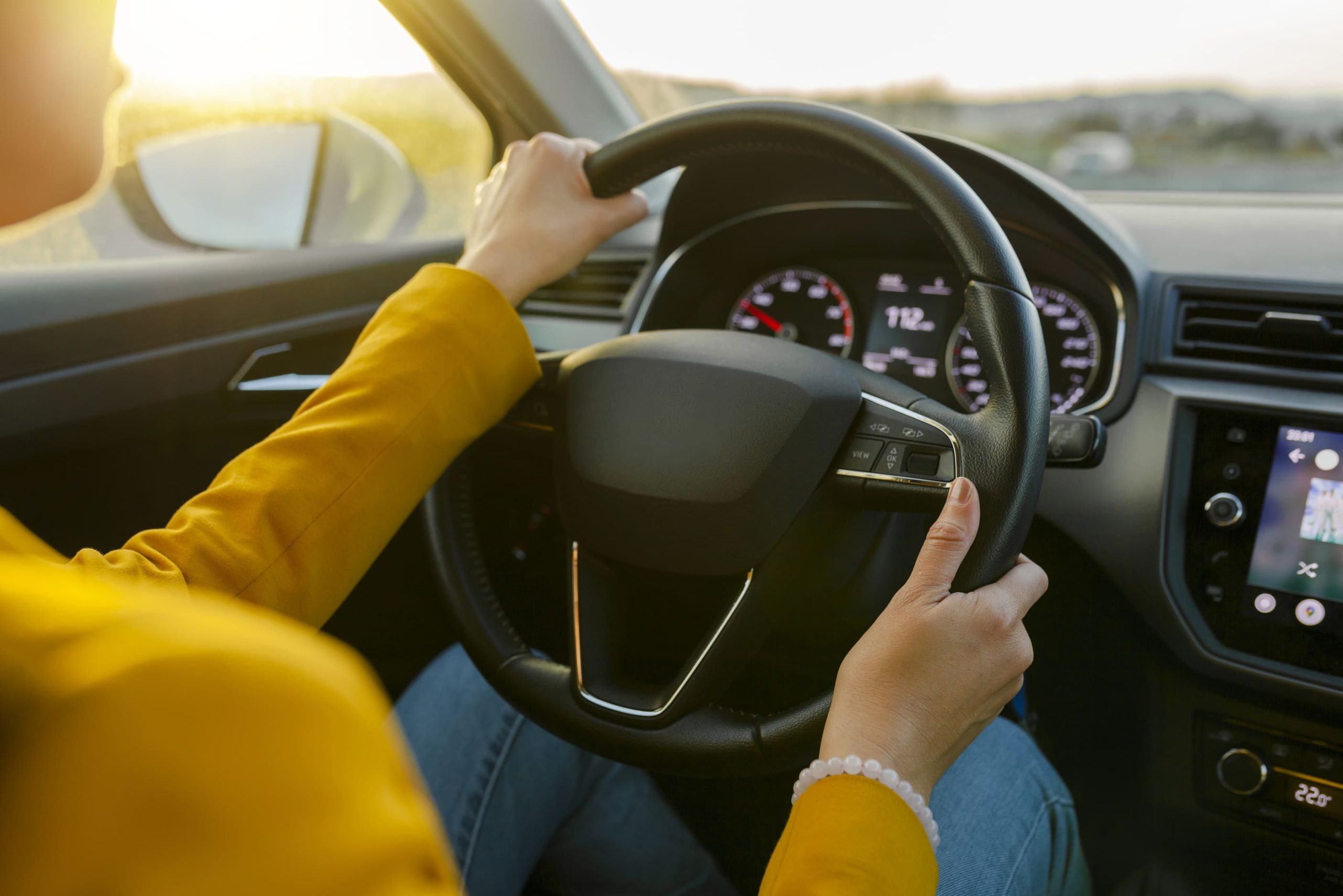 close-up-female-hands-in-yellow-suit-driving-car-o-2023-11-27-05-32-34-utc-1-1-scaled